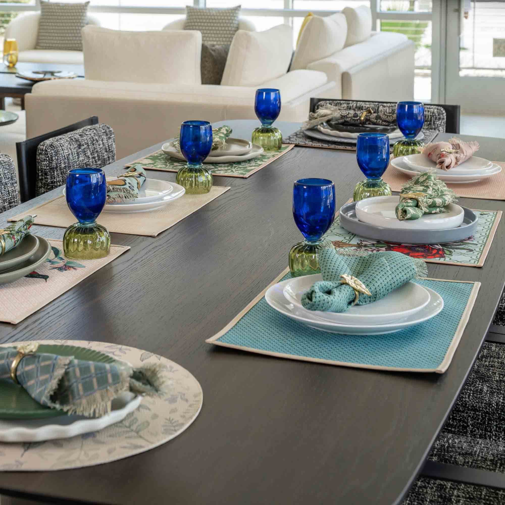 Cobalt goblets and white plates on a long table set with blue and green placemats